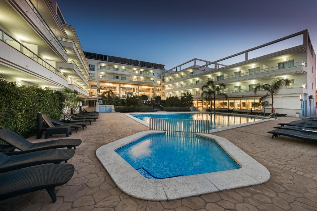阿尔比尔太阳宫阿尔维尔水疗酒店的一座大型建筑,前面设有一个游泳池