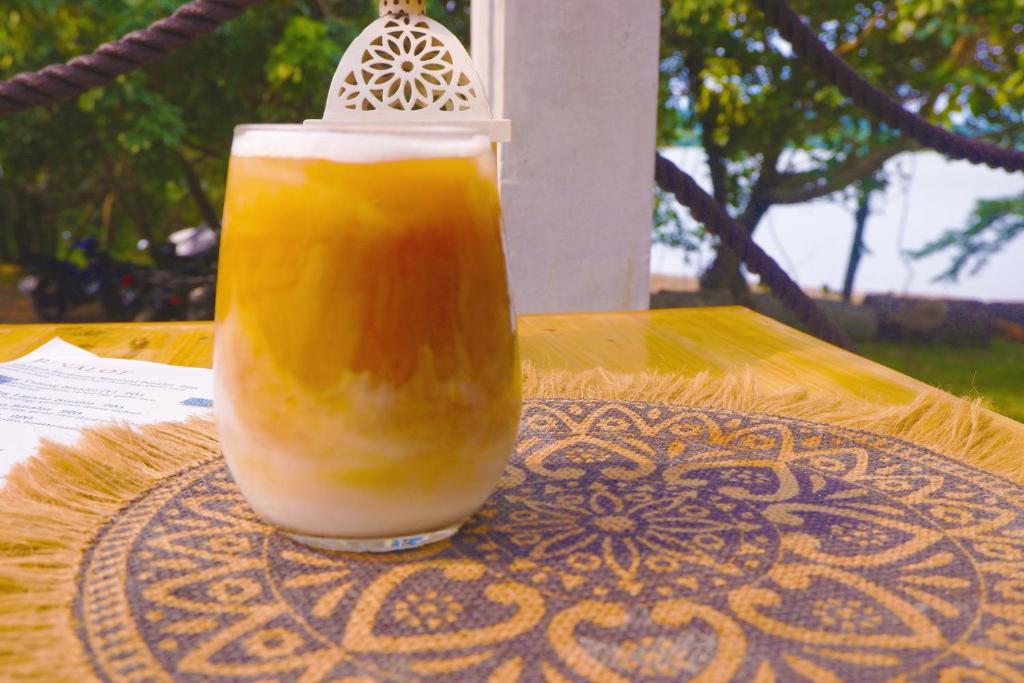 CavintiKaliraya Surf Kamp by Eco Hotel Laguna的坐在桌子上的一杯橙汁