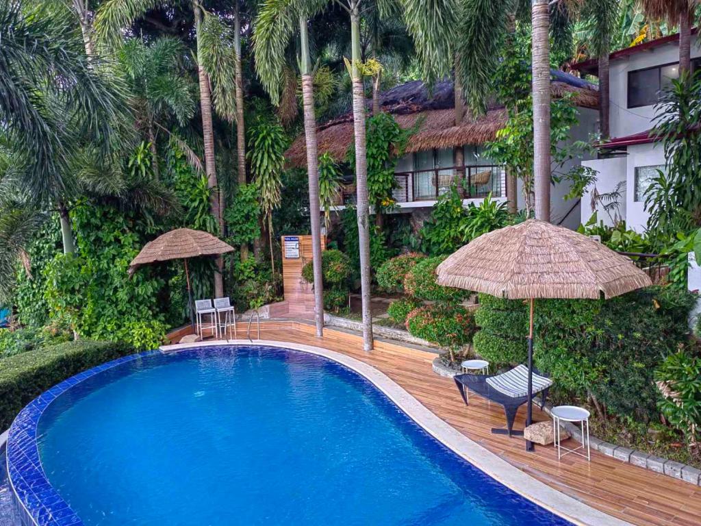 MataasnakahoyVillas by Eco Hotels Batangas的一座带椅子和遮阳伞的游泳池位于一座建筑旁边
