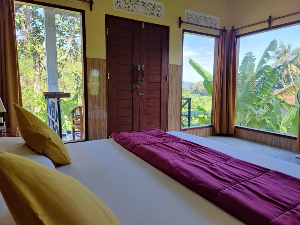 TirtaganggaAlamku Bungalow的配有大窗户的客房内的一张大床