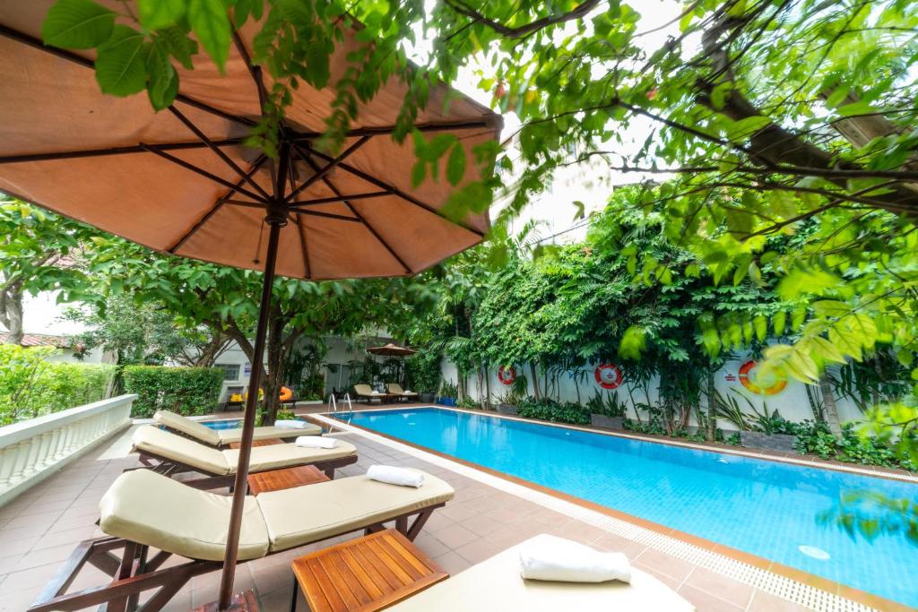 金边Skyline Boutique Hotel Phnom Penh的游泳池旁的遮阳伞和躺椅