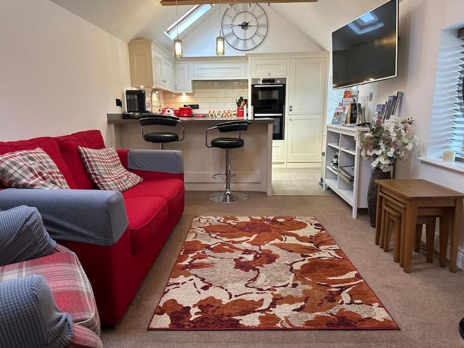 霍尔特The Nest, lovely apartment的一间带红色沙发的客厅和一间厨房