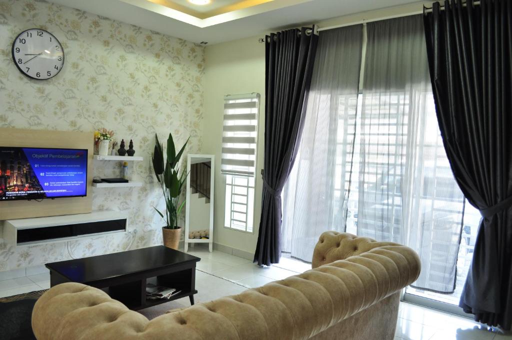 De’ Nuhir Homestay Teluk Senangin的客厅配有沙发和墙上的时钟
