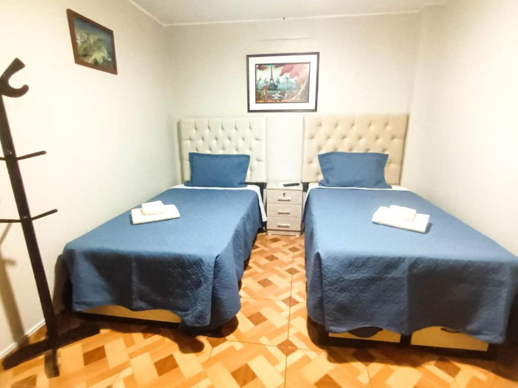 利马Habitación 2 camas a pasos del Aeropuerto Lima的配有蓝色床单的客房内的两张床