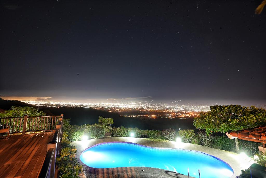 阿拉胡埃拉Villas Aracari的享有城市美景的夜间游泳池