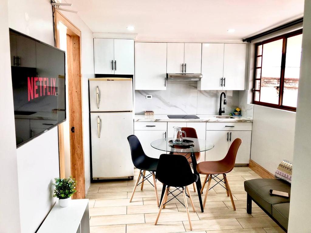 昆卡Family Apartment centro ciudad + Netflix的厨房配有白色橱柜和桌椅