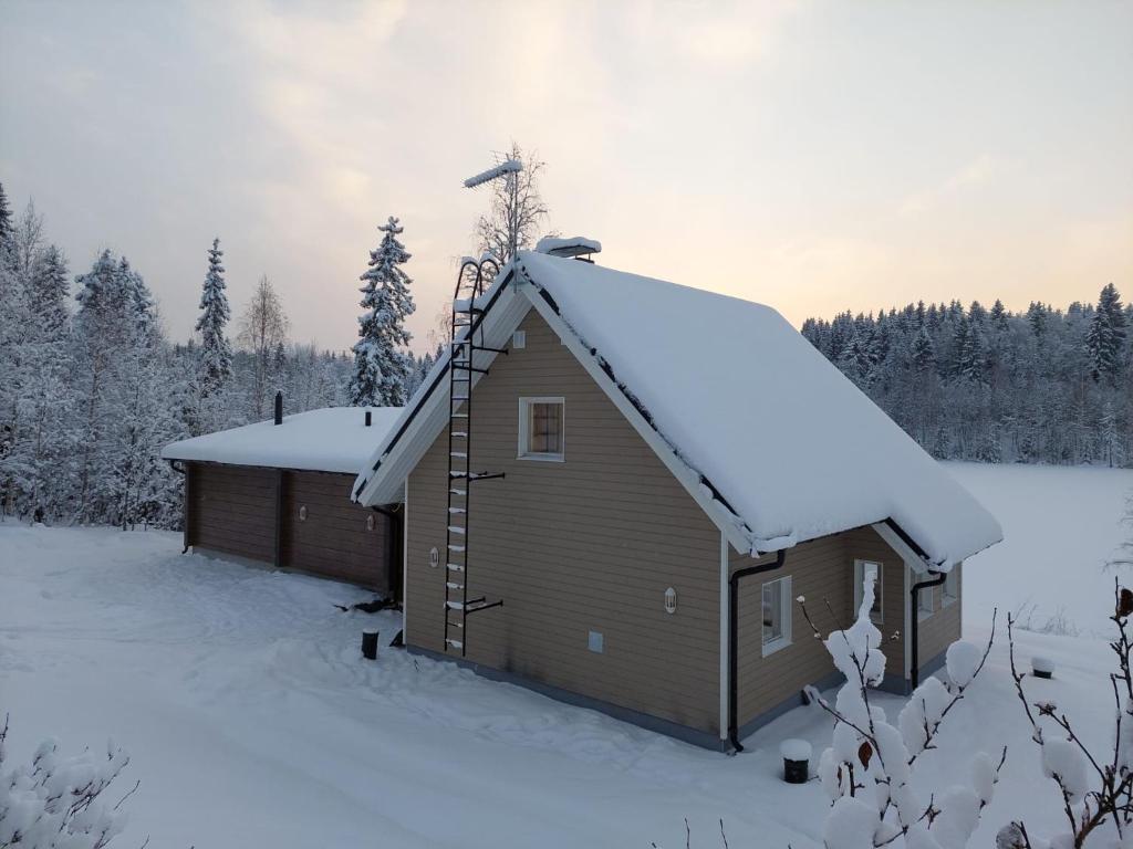 UurainenMökki ulkoporealtaalla的雪地中带雪盖屋顶的建筑