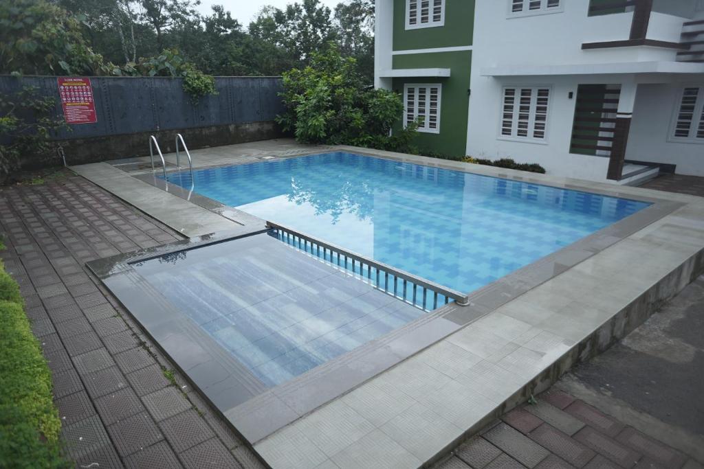 瓦亚纳德Luxe Hotel - Rooms & Villas Wayanad的一座房子旁的院子内的游泳池