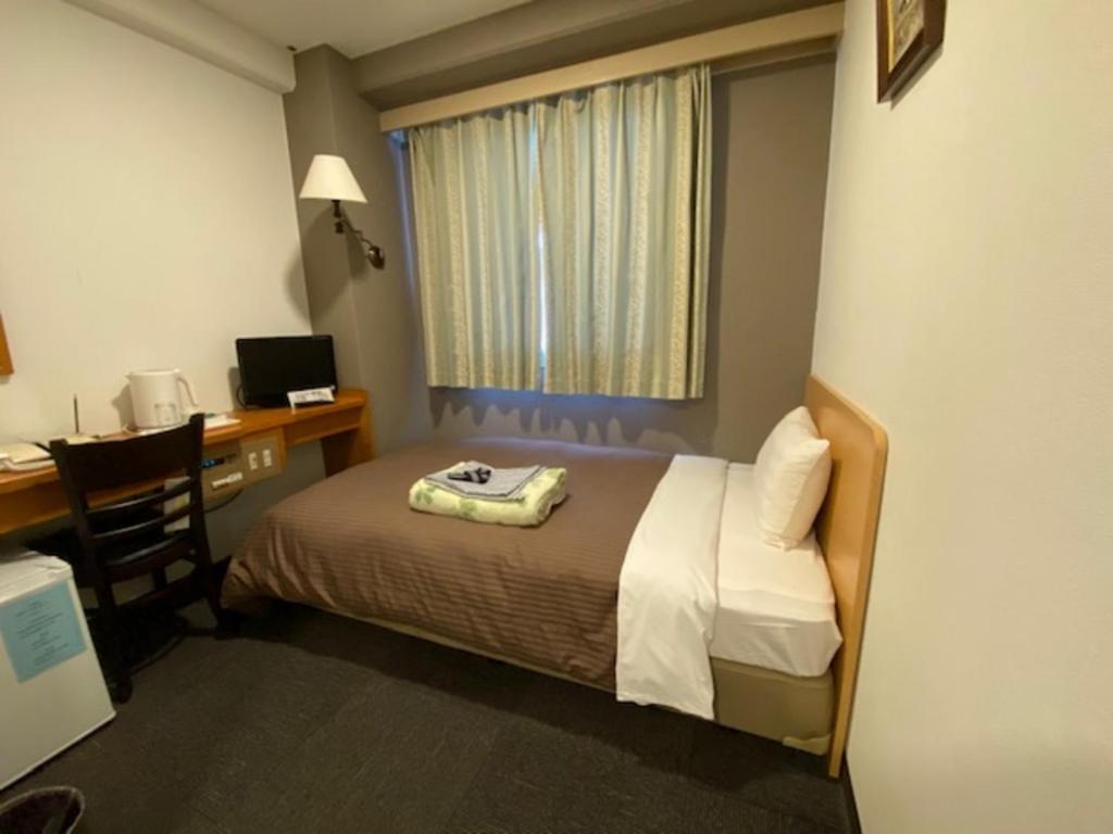 泉佐野Hotel New Yutaka - Vacation STAY 35249v的客房设有一张床、一张桌子和一台电脑