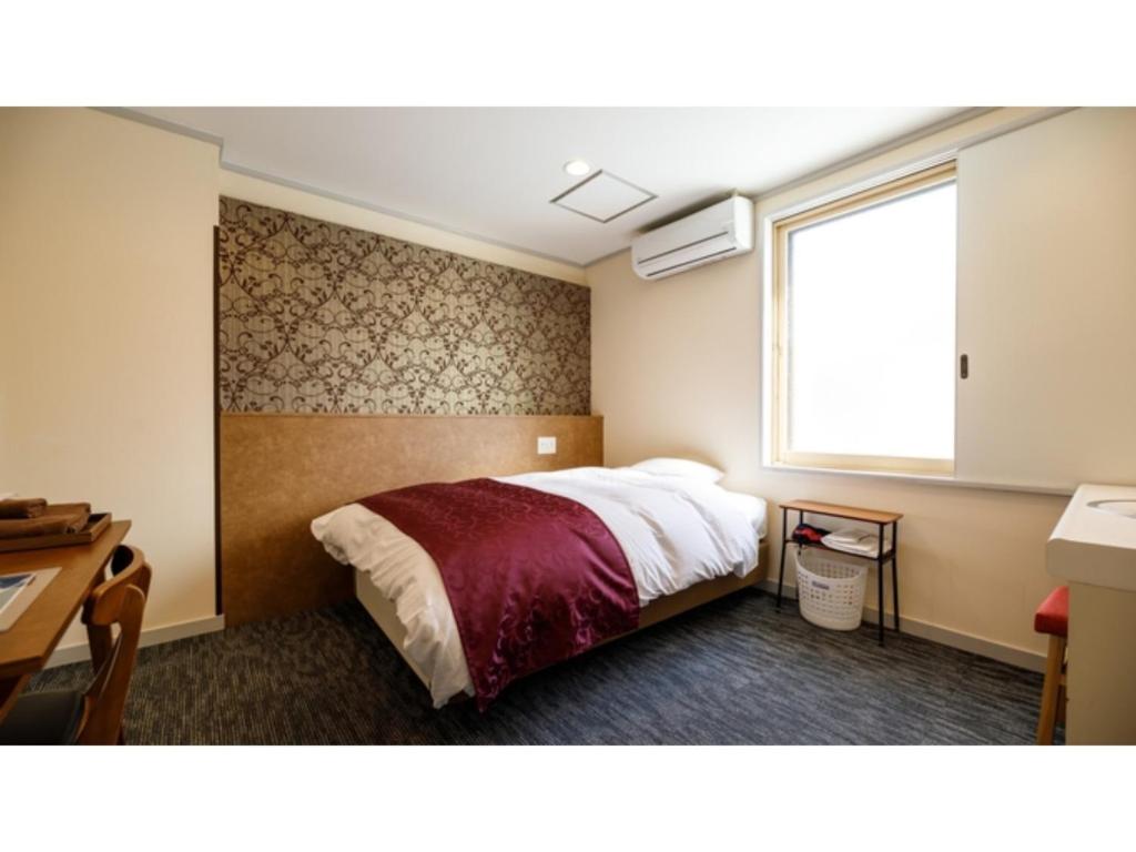 金泽Kanazawa Station Hotel - Vacation STAY 36362v的一间卧室配有一张床、一个窗口和一张书桌