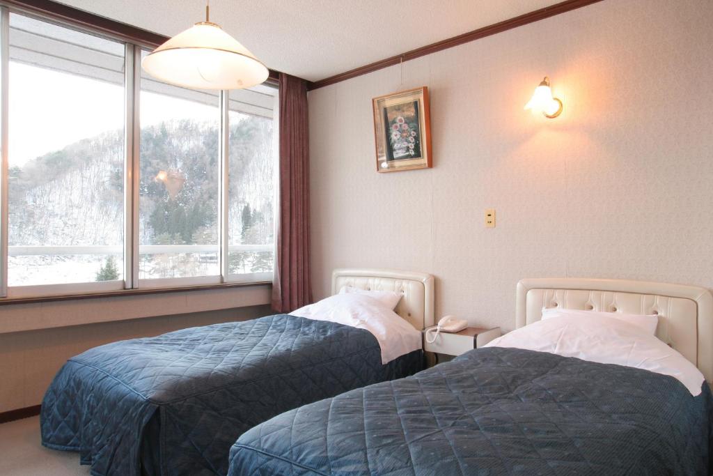 富士河口湖山田日式旅馆的酒店客房设有两张床和窗户。