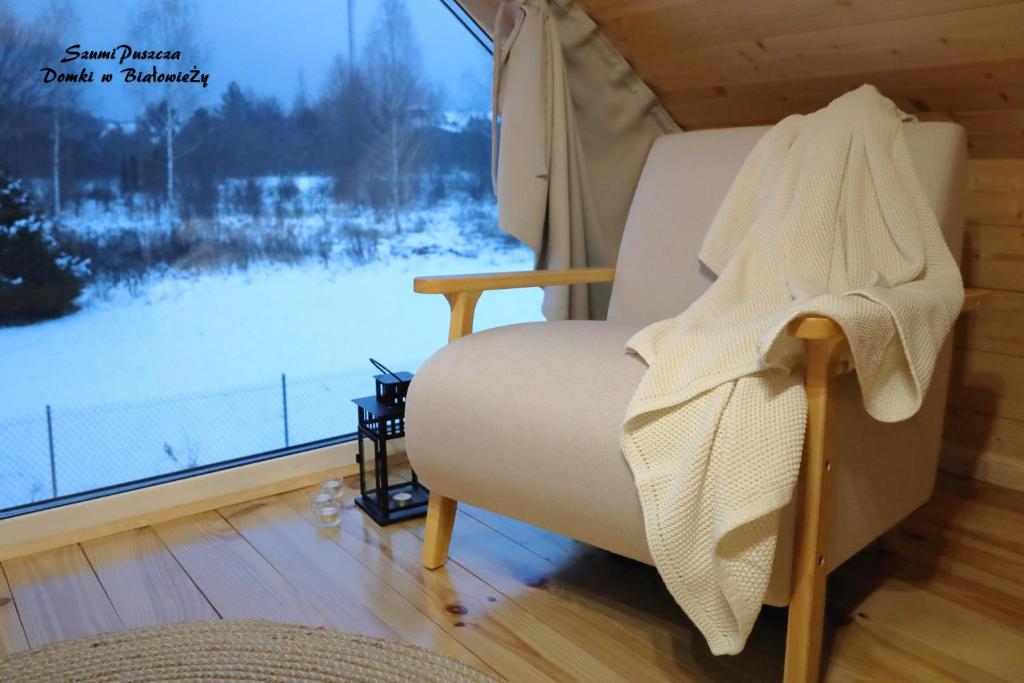 比亚沃维耶扎SzumiPuszcza - domki, sauna, jacuzzi的窗户客房内的白色椅子