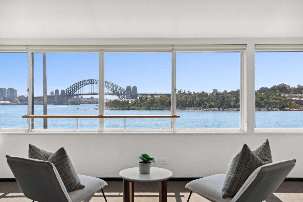 悉尼Balmain Wharf l 2 Bedroom Apartment的一间配备有椅子的客房,享有Sydney海港大桥的景致。