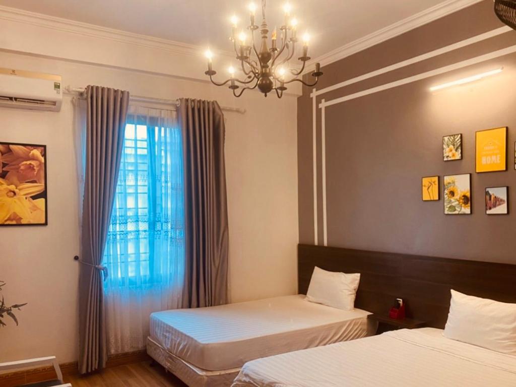 Phú ThọMộc Hương Hotel的一间卧室设有两张床和一个带吊灯的窗户。