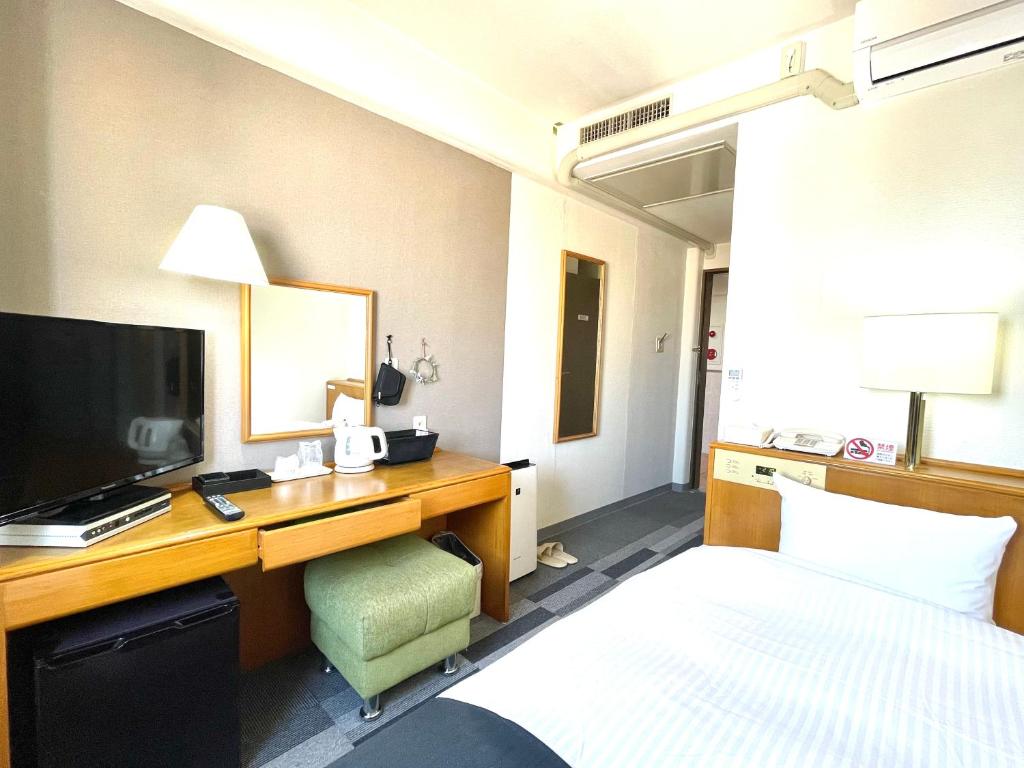 青森Aomori Green Park Hotel的酒店客房配有一张床和一张书桌及一台电视