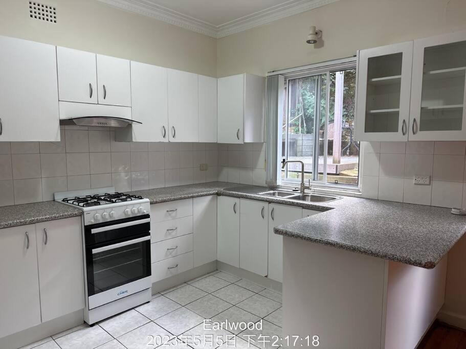 悉尼3 BDR house close to train station, airport & City的厨房配有白色橱柜和炉灶烤箱。