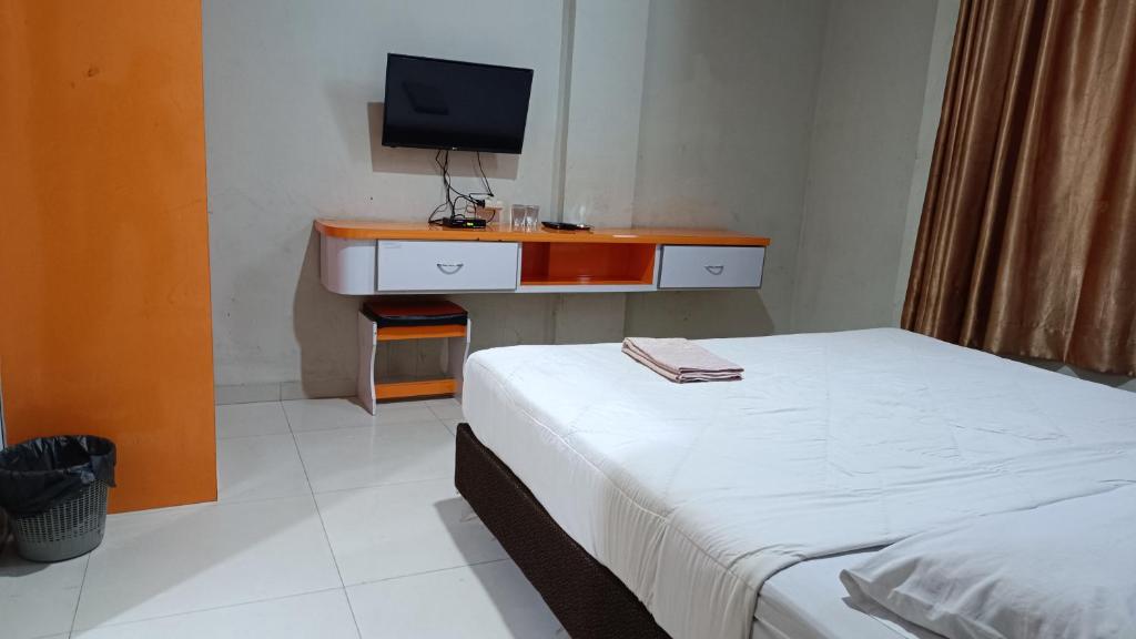 北干巴鲁IHomestay Pekanbaru的一间卧室配有一张床和一张书桌及电视