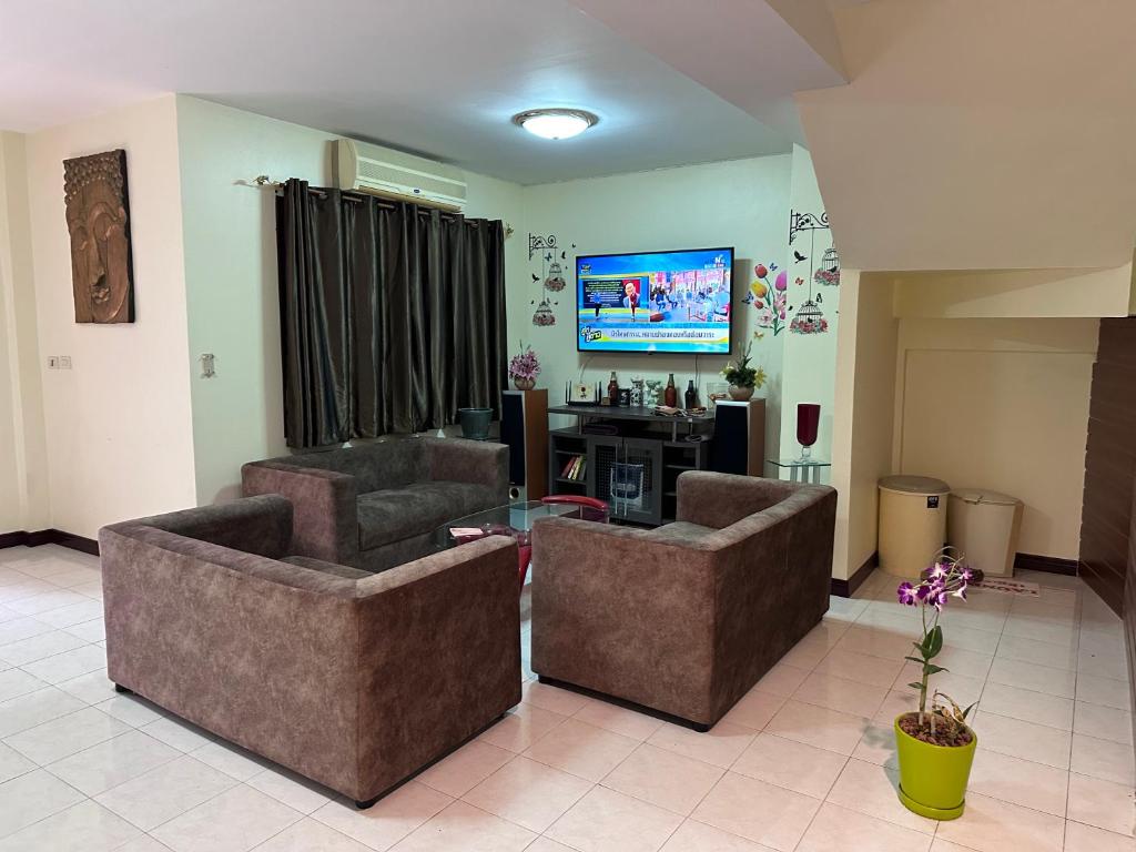 芭东海滩Hideaway House Patong的客厅配有两张沙发和一台电视机