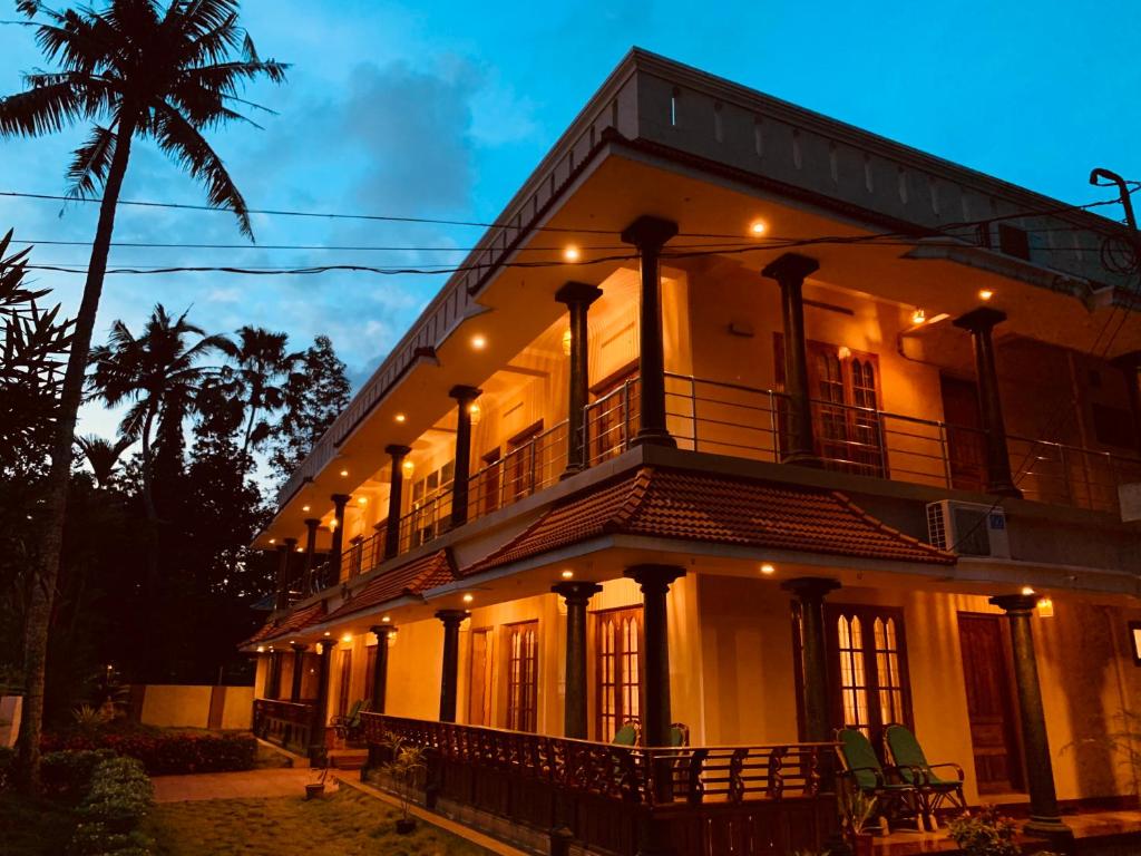 瓦尔卡拉Surendram Villa的一座大型白色建筑,设有阳台和棕榈树