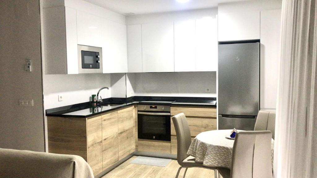 阿吉拉尔日波奥Apartamento La Muralla 2D的厨房配有桌子和不锈钢冰箱。