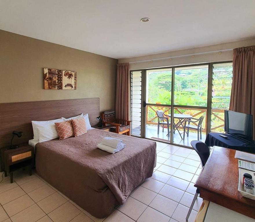 阿皮亚萨摩亚瓦伊酒店的一间卧室配有一张床、一台电视和一个阳台