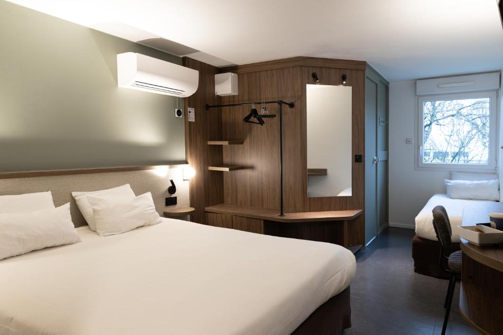 卢德南南锡 - 卢德斯基里亚德酒店的卧室配有白色的床、书桌和窗户。