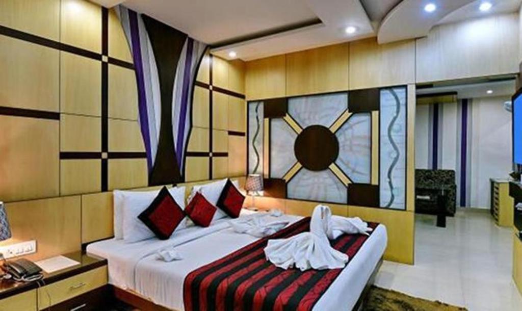 穆扎夫法尔普尔FabHotel Prime Simna International的卧室配有一张大床,墙上挂着时钟