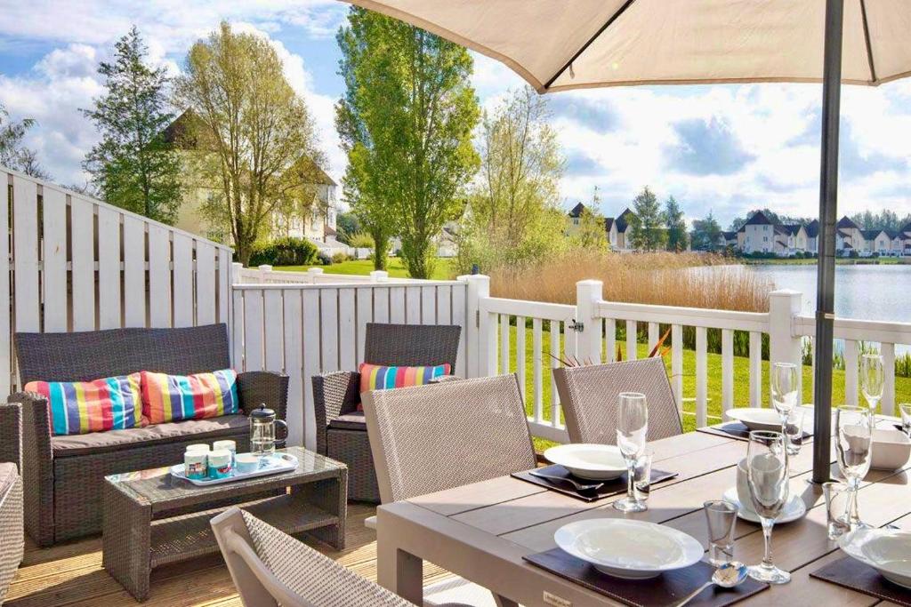 南塞尔尼Spinnaker Lodge · Cotswolds Lakeside Home的庭院配有桌椅和遮阳伞。