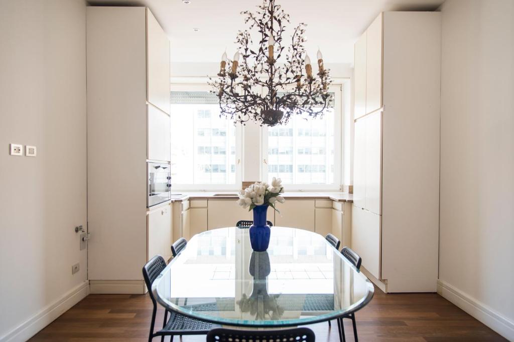 米兰Vittore Rooms & Apartment的一间带玻璃桌和吊灯的用餐室