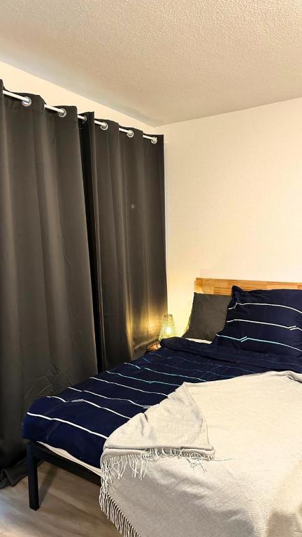 杜伊斯堡Modern Studio - perfect location的一间卧室配有一张带蓝色床单和窗帘的床
