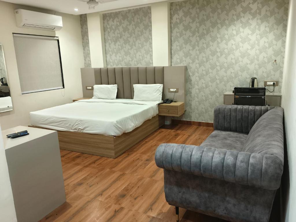 勒克瑙Hotel Sharma Regency的一间卧室配有一张床、一张沙发和一把椅子