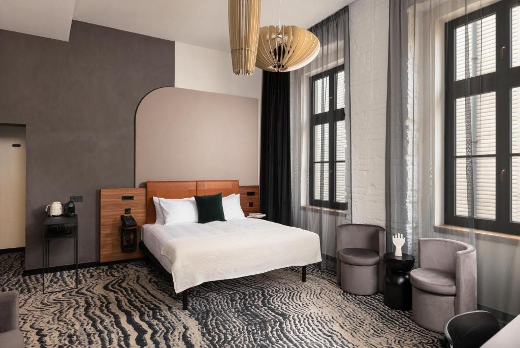 布达佩斯Hotel GIN Budapest的一间卧室配有一张床、一把椅子和窗户。