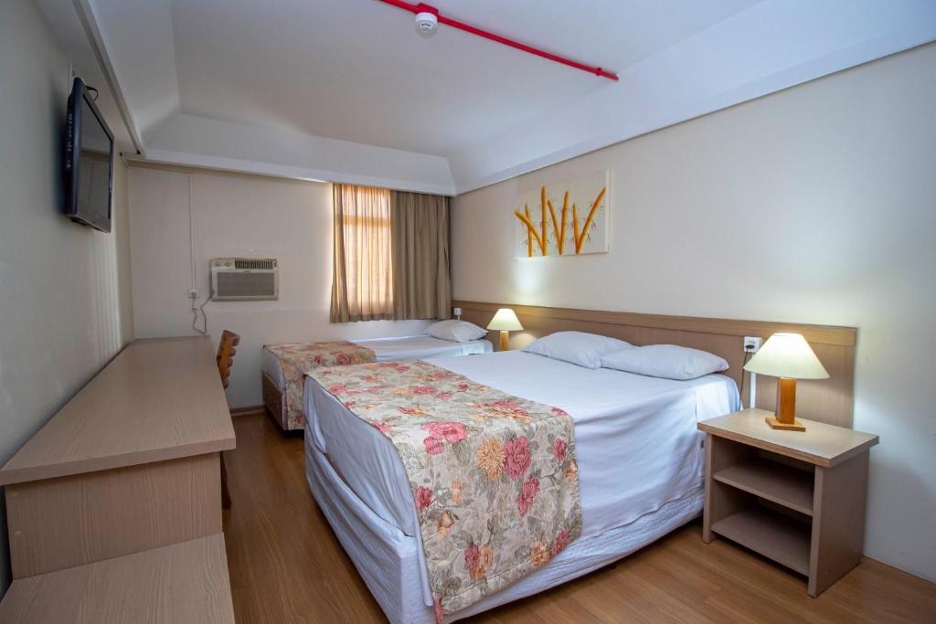 库里提巴Hotel Golden Park Curitiba的酒店客房设有两张床和窗户。