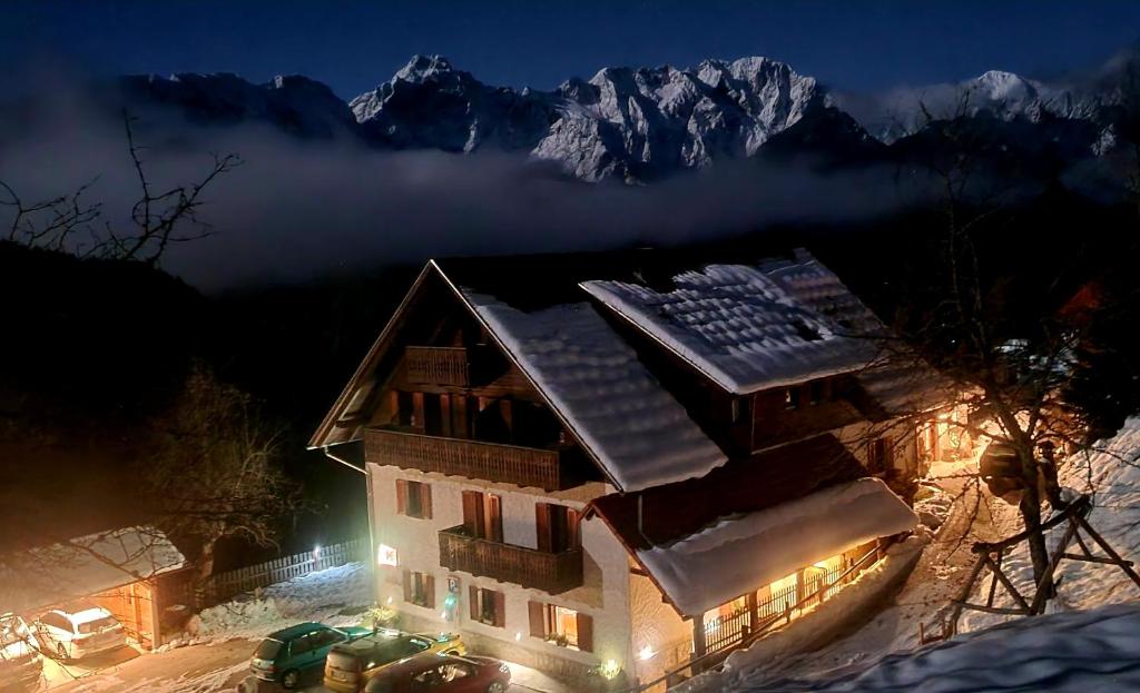 索尔察瓦Farm Stay "Alpine Dreams"的雪中的房子,晚上有雪的山