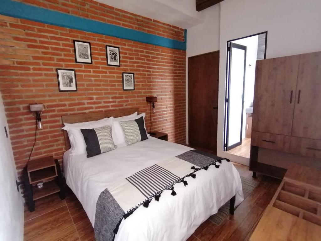 圣克里斯托瓦尔-德拉斯卡萨斯Suites del Barrio的一间卧室设有一张带砖墙的大床