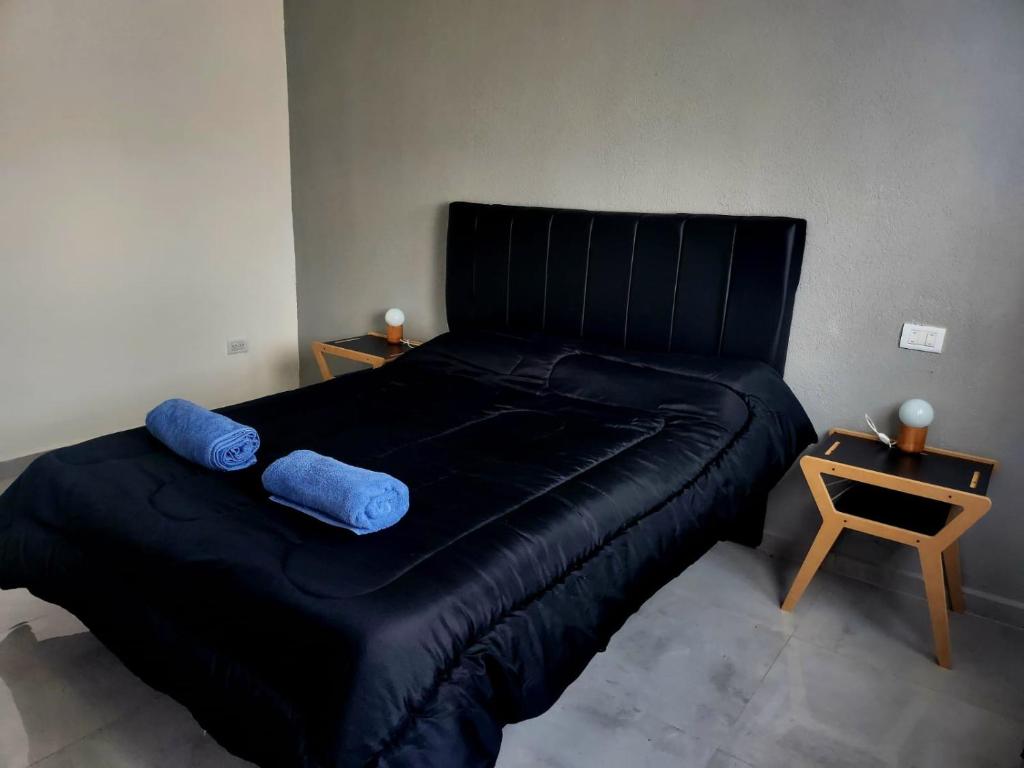 内科切阿F&E Apartment的一张黑色的床,上面有两个蓝色的枕头