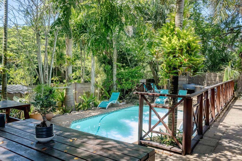 圣卢西亚African Dreamz Guest House的一个带木甲板和桌椅的游泳池