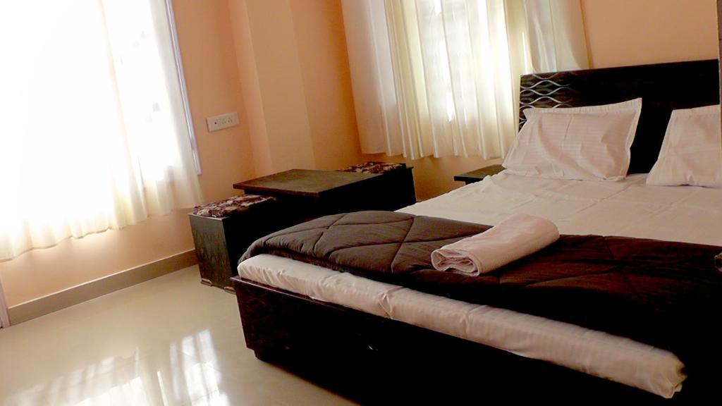 西姆拉Lakshay Regency的一间卧室配有一张床、一张桌子和一个窗户。