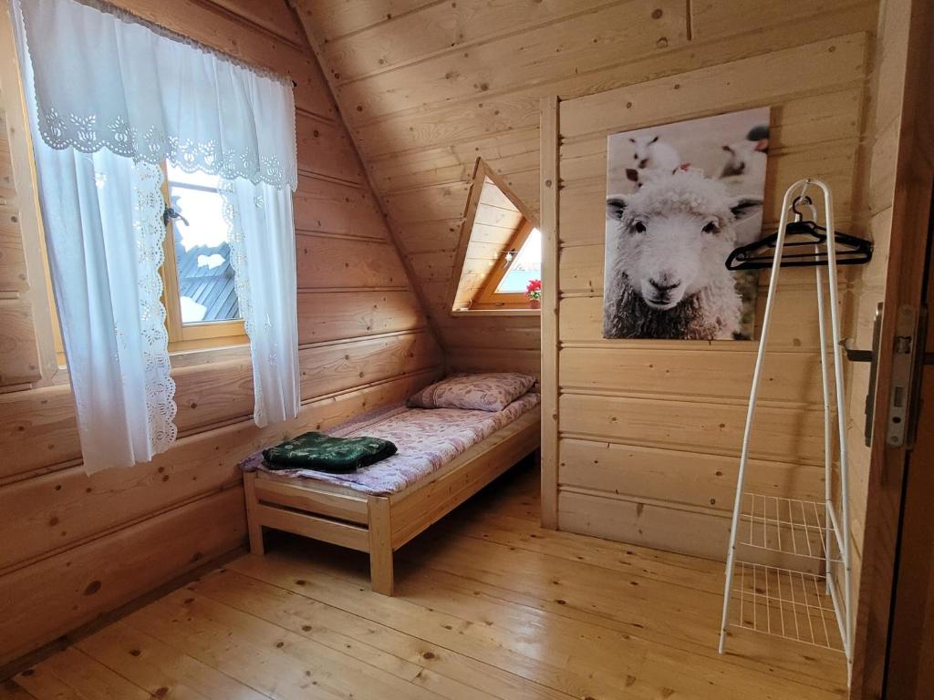 DzianiszDomek u Beaty的小屋内一张床位的房间,里面放着一幅羊的照片