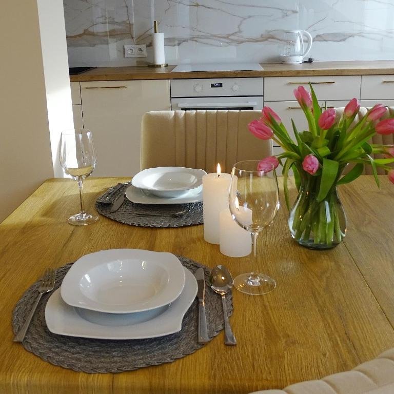耶莱尼亚古拉Apartamenty u ROXI的一张桌子,上面有盘子和玻璃杯,花瓶
