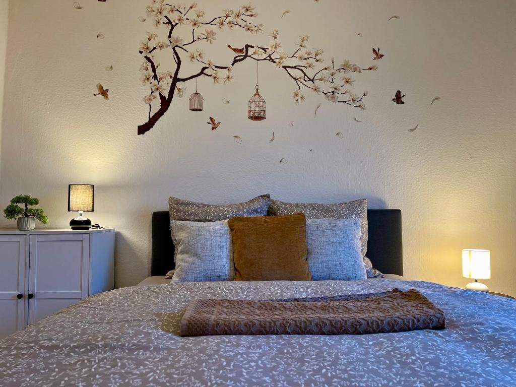 兰讷斯Dejlig 2 værelses lejlighed的卧室配有一张床铺,墙上挂着一棵树