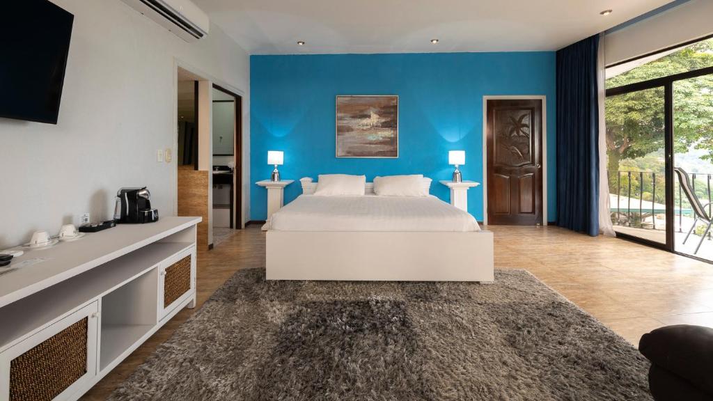 曼努埃尔安东尼奥Blue Mirador Hotel Manuel Antonio的一间卧室设有一张床和蓝色的墙壁