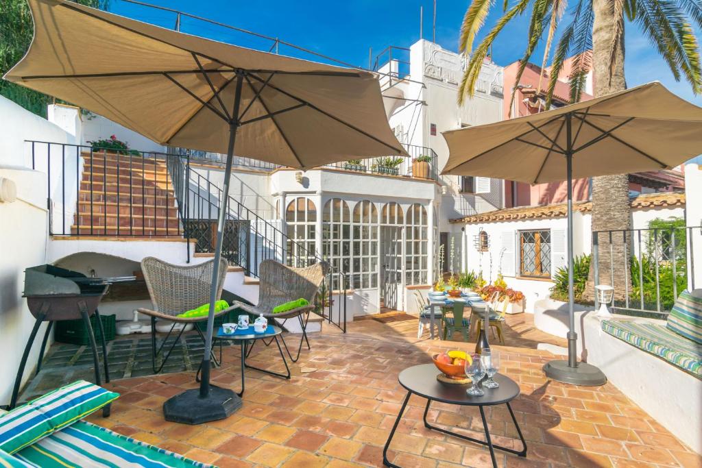马略卡岛帕尔马Villa El Terreno的天井配有两把遮阳伞和桌椅。