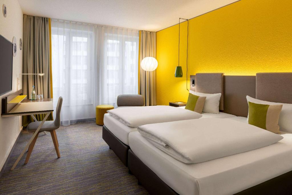 莱比锡Vienna House Easy by Wyndham Leipzig的酒店客房配有两张床和一张书桌