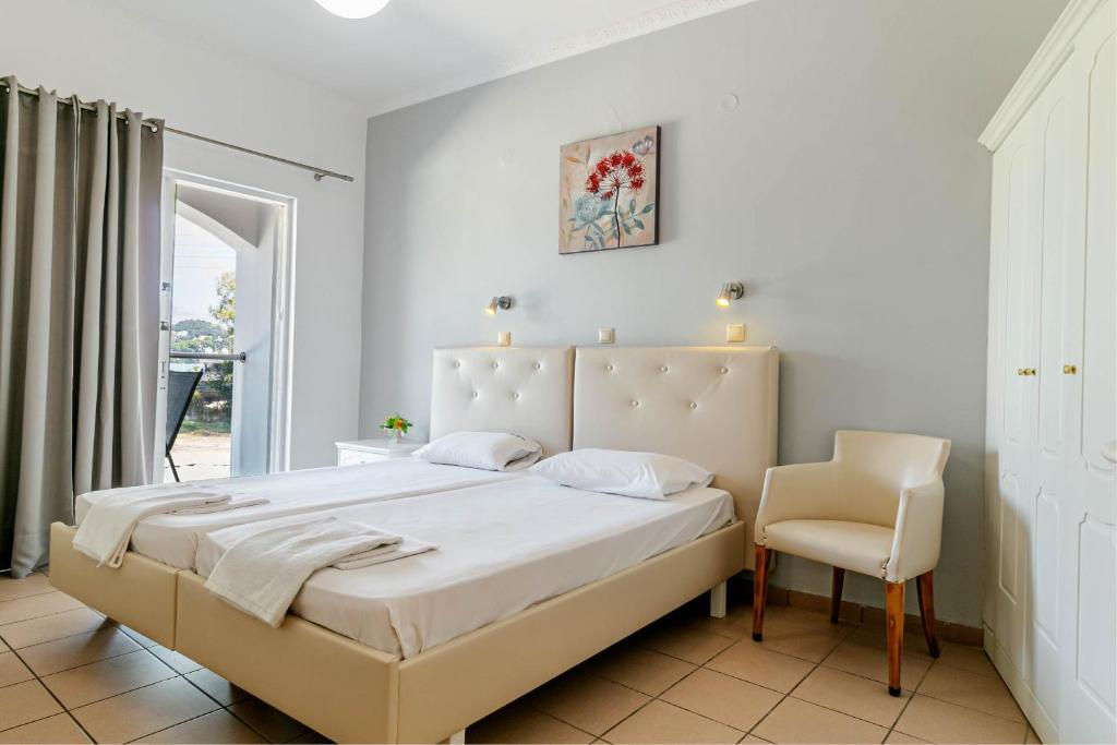 古维亚Porto Marina Aparthotel的一间卧室配有一张大床和一把椅子