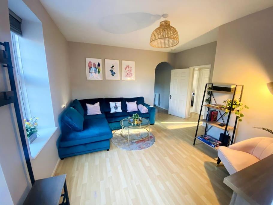 温彻斯特City Centre Riverside Apartment的客厅配有蓝色的沙发和玻璃桌