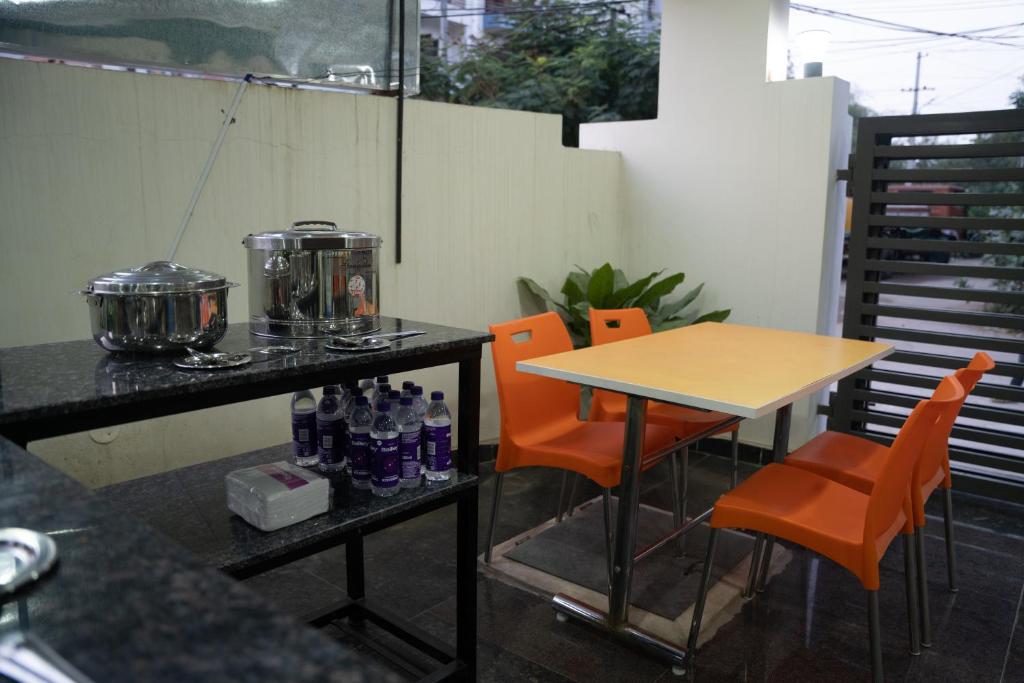 海得拉巴Yellow Bells Gachibowli的一张桌子、橙色椅子和一张桌子,上面有饮料