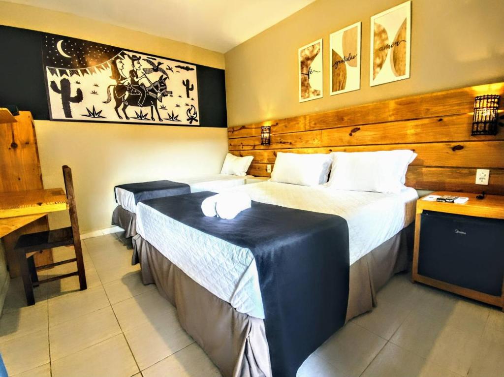 阿拉卡茹Vila Aju - Pousada Temática的酒店客房设有两张床和一张桌子。