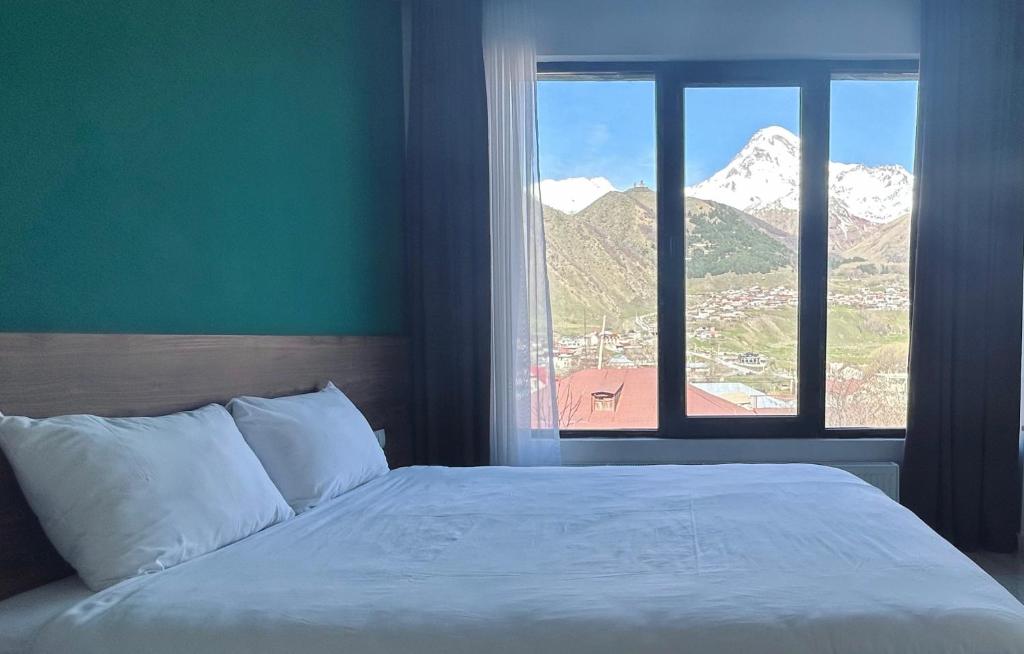 卡兹贝吉Shushabandi Kazbegi的一间卧室设有一张床和一个享有山景的窗户。