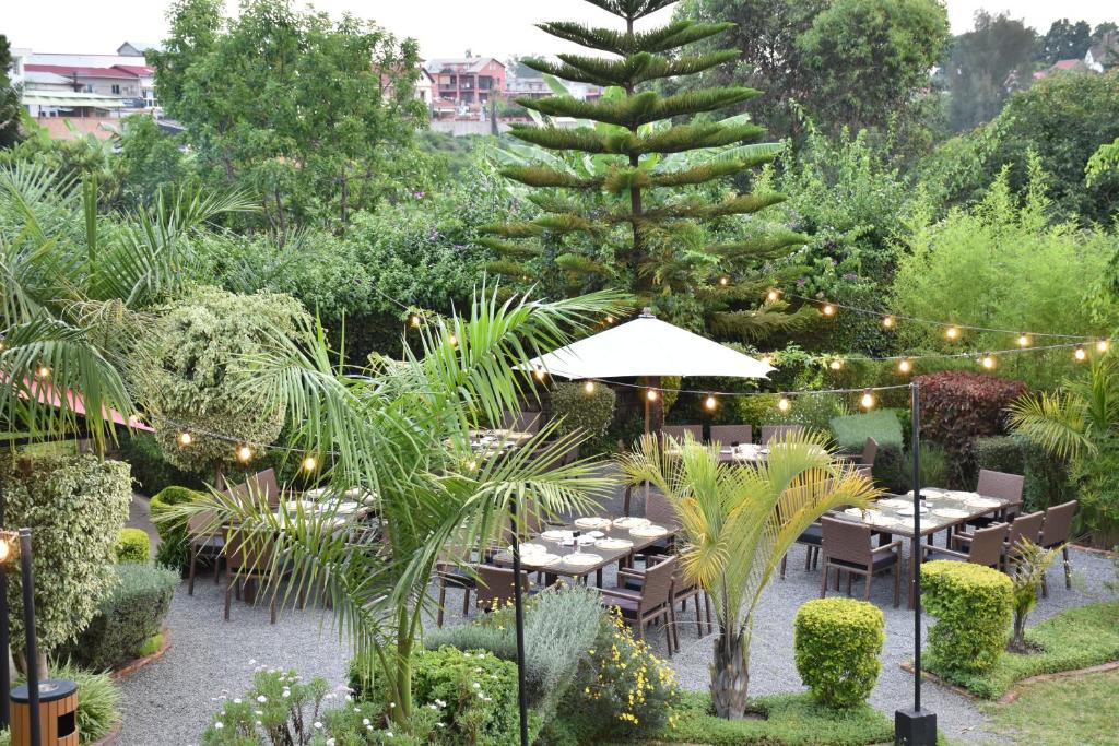 塔那那利佛San Cristobal Boutique Hotel - Ivato Airport的花园设有桌子和 ⁇ 萝树及灯